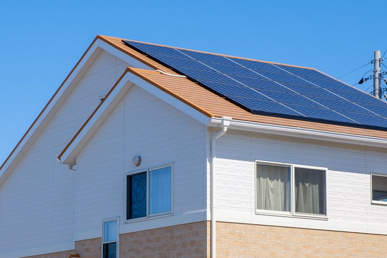 Ein modernes Wohnhaus unter klarem blauem Himmel, ausgestattet mit Solarpanelen auf dem Dach zur Energiegewinnung. Das Haus verfügt über eine weiße und beige Fassade und zeigt, wie nachhaltige Energienutzung in der heutigen Architektur integriert wird.