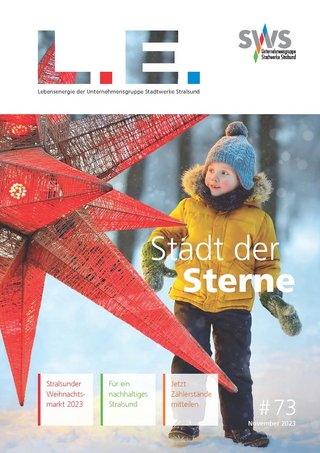 Das Bild zeigt das Cover einer Ausgabe von "L.E. Magazin", mit dem Titel "Stadt der Sterne". Im Vordergrund ist ein Kind in Winterkleidung, das an einer großen roten Sternskulptur steht. Im Hintergrund ist verschwommen eine winterliche Stadtlandschaft zu erkennen.