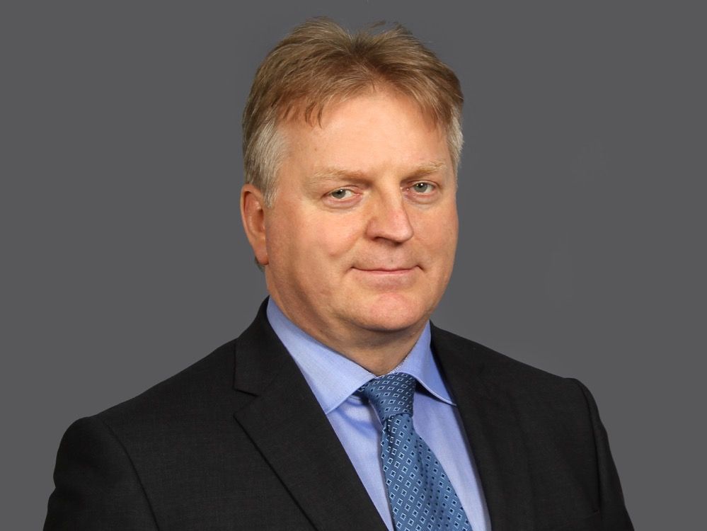 Geschäftsporträt eines leitenden Angestellten mit entschlossenem Blick, trägt einen dunklen Anzug und ein blaues Hemd mit passender Krawatte, vermittelt Kompetenz und Professionalität im Kontext der Stadtwerke.