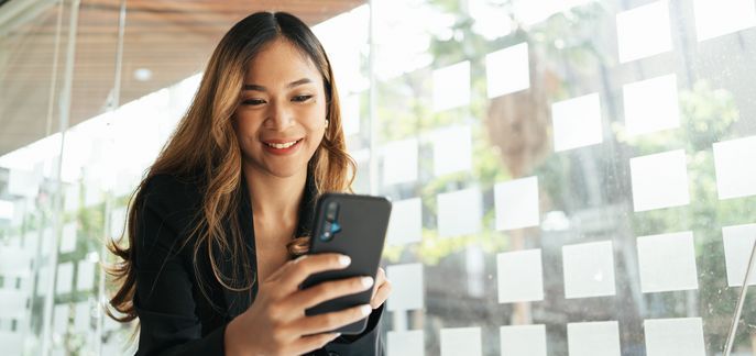 Frau interagiert und schaut auf ihr Handy in einem beleuchteten Raum.