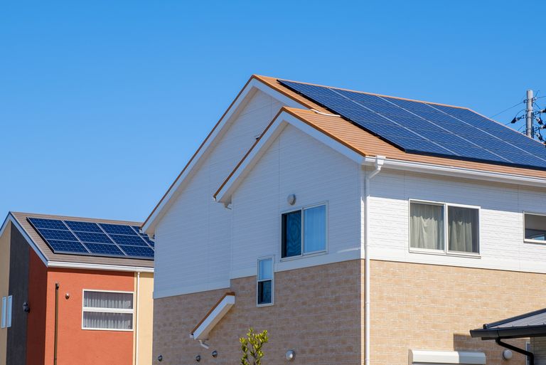 Ein modernes Wohnhaus unter klarem blauem Himmel, ausgestattet mit Solarpanelen auf dem Dach zur Energiegewinnung. Das Haus verfügt über eine weiße und beige Fassade und zeigt, wie nachhaltige Energienutzung in der heutigen Architektur integriert wird.