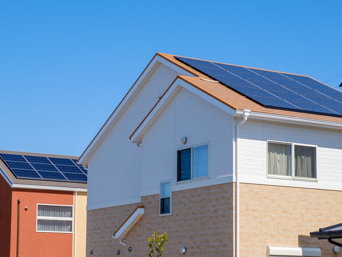 Ein modernes Wohnhaus unter klarem blauem Himmel, ausgestattet mit Solarpanelen auf dem Dach zur Energiegewinnung. Das Haus verfügt über eine weiße und beige Fassade und zeigt, wie nachhaltige Energienutzung in der heutigen Architektur integriert wird.