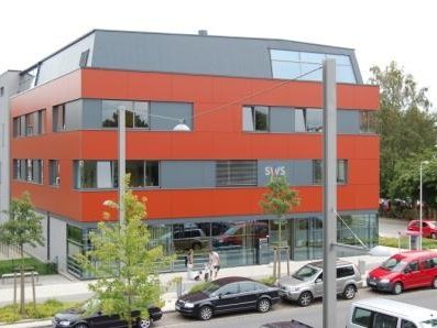 Das moderne Service-Center der Stadtwerke Stralsund mit einer auffälligen roten Fassade, großen Fenstern und geparkten Autos im Vordergrund.