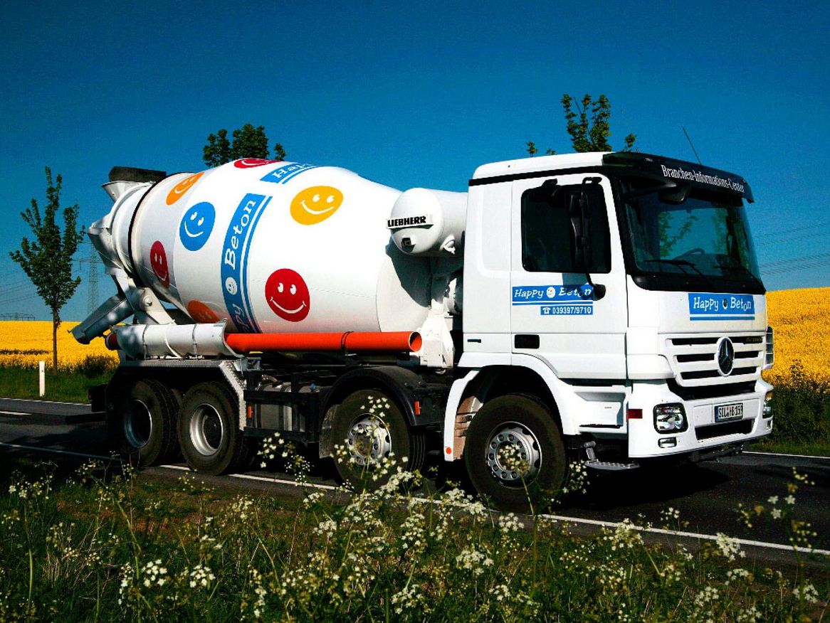 Happy Betonmischer Betonmischer auf dem Weg zur Baustellen, fährt an Rapsfeldern vorbei