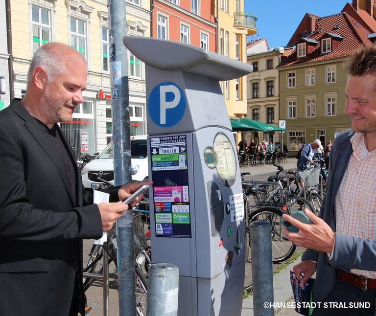Zwei Menschen stehen an einem Parkautomaten