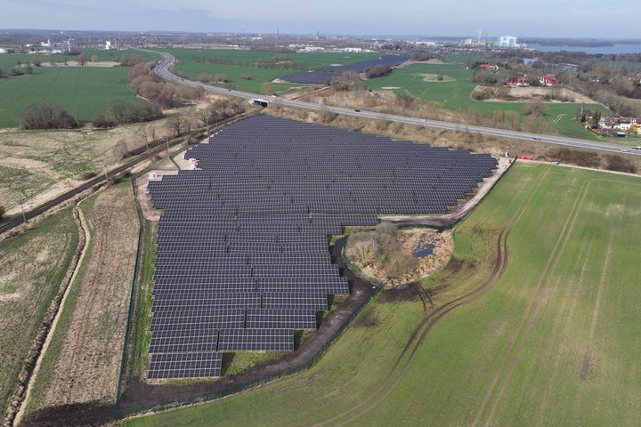 Luftaufnahme des Solarparks Voigdehagen II, umgeben von grünen Feldern und vereinzelten Gebäuden im Hintergrund.