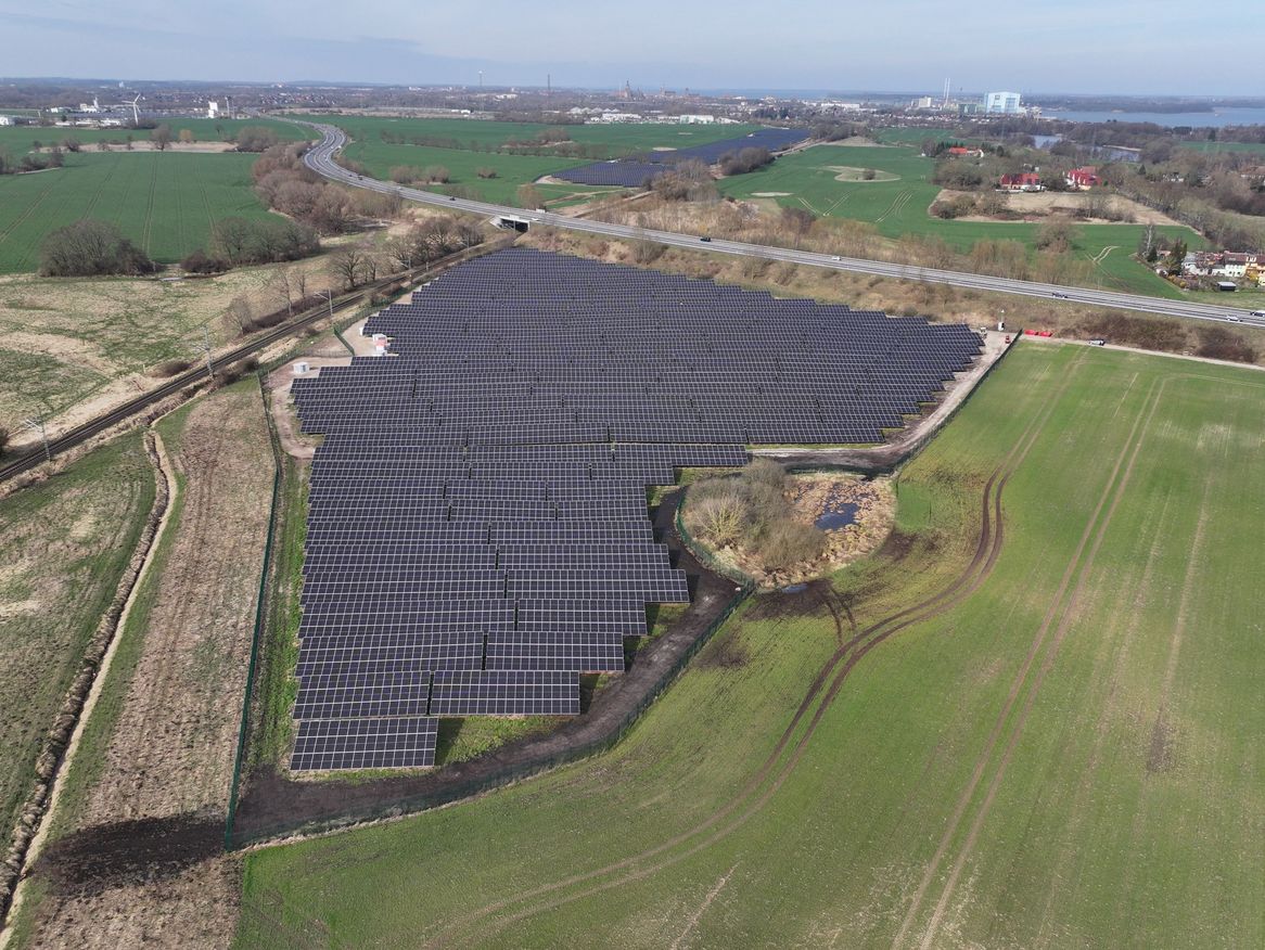 Luftaufnahme des Solarparks Voigdehagen II, umgeben von grünen Feldern und vereinzelten Gebäuden im Hintergrund.