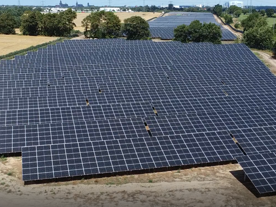 Ein weitläufiges Solarkraftwerk mit zahlreichen Photovoltaik-Paneelen in einer ländlichen Umgebung, das grüne Energieerzeugung unter dem klaren Himmel demonstriert.