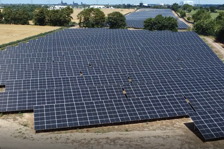Ein weitläufiges Solarkraftwerk mit zahlreichen Photovoltaik-Paneelen in einer ländlichen Umgebung, das grüne Energieerzeugung unter dem klaren Himmel demonstriert.