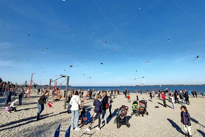 Ein belebter Strand voller Menschen, die die Sonne genießen, mit einem klaren blauen Himmel, der die sommerliche Atmosphäre an der Küste unterstreicht.