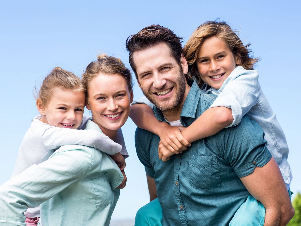  Ein Paar hält zwei Kinder auf den Schultern, was eine herzliche und liebevolle Familie darstellt.