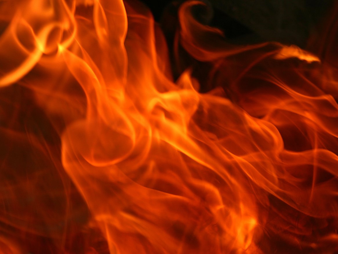 Eine Nahaufnahme von lebhaften, tanzenden Flammen, die Energie und Hitze ausstrahlen, eingefangen in einem Bild, das die dynamischen Muster und warmen Farbtöne des Feuers zeigt.